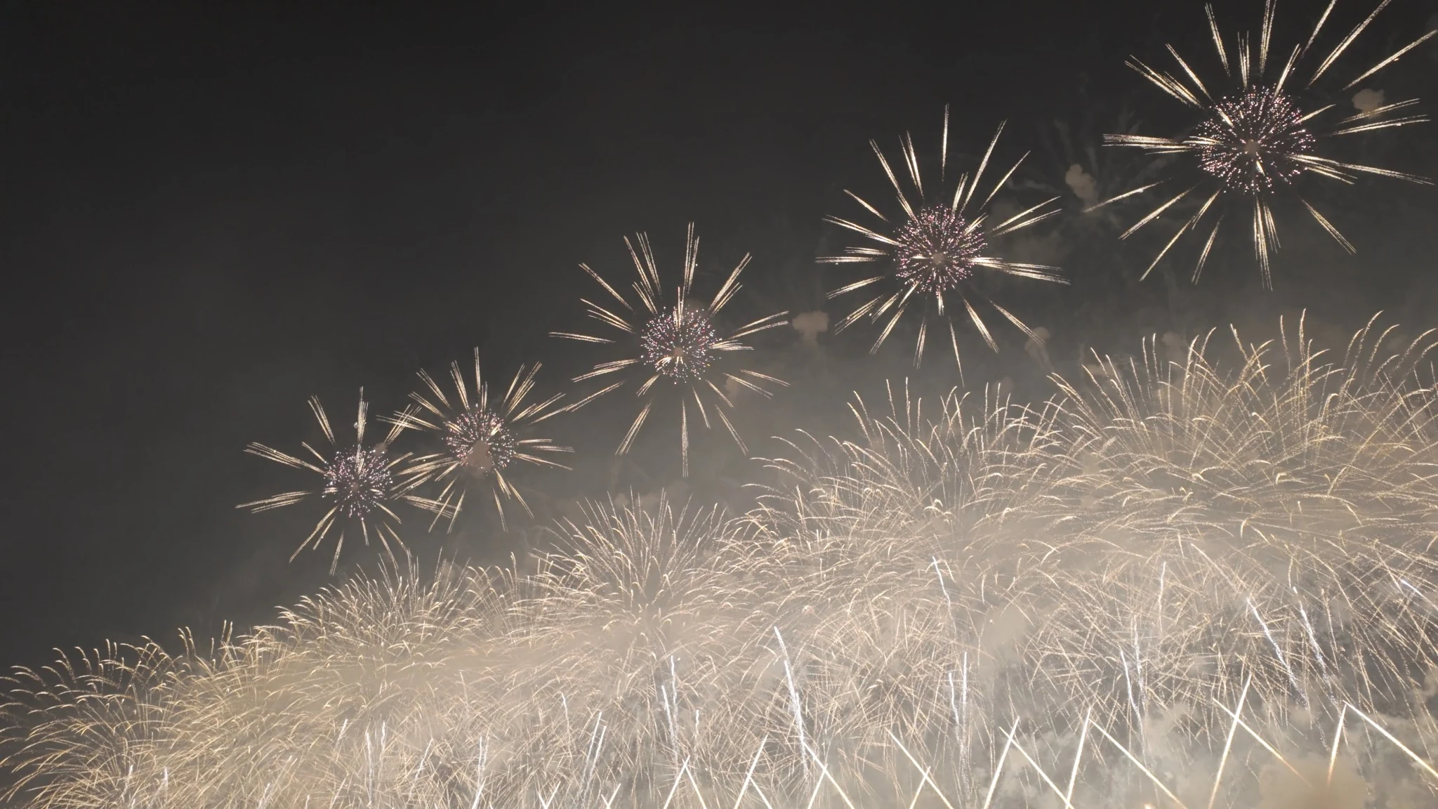 A wide curtain of golden fireworks above the Omagari competition grounds