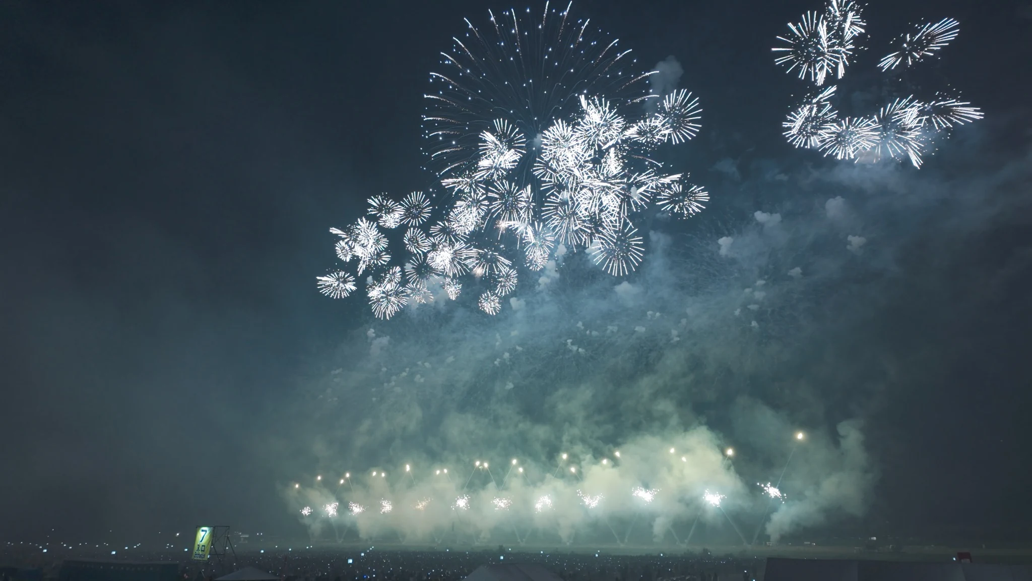 Bright white fireworks spreading across the night sky at Omagari