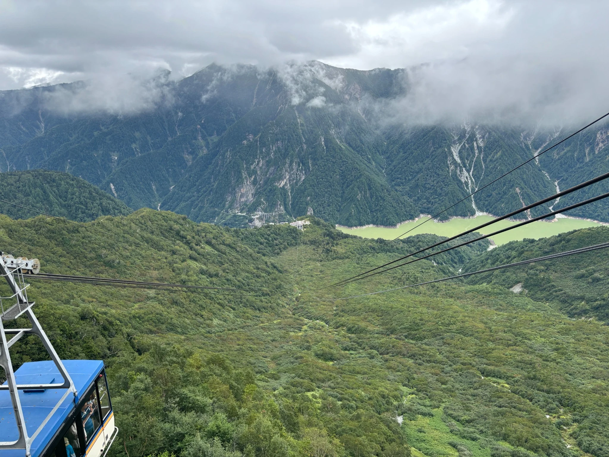 Cable car descending through a steep green valley on the Tateyama Kurobe Alpine Route